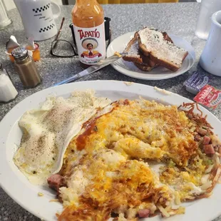 Hash brown sandwich with sausage, ham, bacon, and cheese. Whole wheat toast- butter on the side and two eggs over medium.