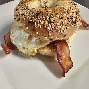 a bagel sandwich with bacon and eggs