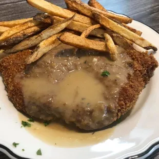 a piece of chicken with gravy and french fries