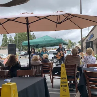 a group of people sitting at tables under umbrellas