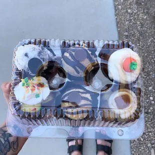 a person holding a box of cupcakes