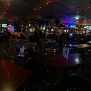 a bar with tables, chairs, and televisions