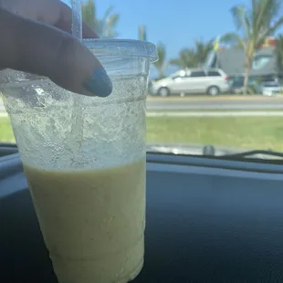 a hand holding a drink in a plastic cup