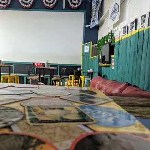 a view of a classroom with tables, chairs, and a projector screen