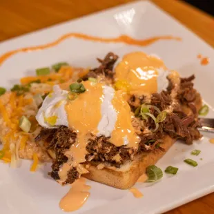 Smoked Brisket Bennie - poached eggs, roasted red pepper hollandaise, Texas toast, served with spicy cheese grits.