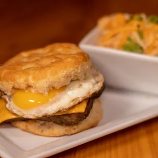 Sausage McOutpost - two flaky biscuits, sunny eggs, sausage, American cheese served with spicy cheese grits
