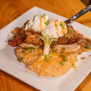 Hot Fried Chicken Bennie - poached eggs, bacon, Tasso cream, sauce, flaky biscuit, served with spicy cheese grits.
