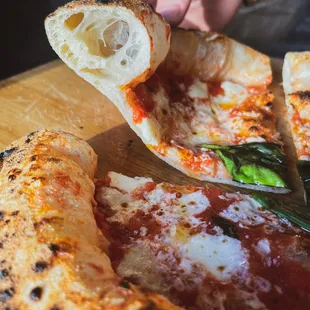 a person taking a slice of pizza