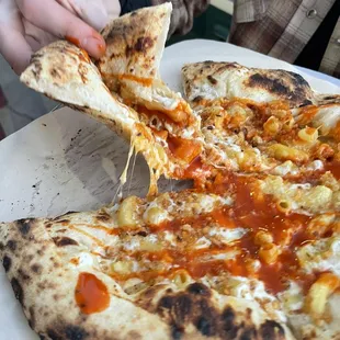 a person taking a slice of pizza