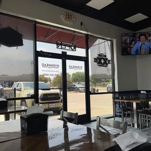 The dining area, tables, chairs, napkin holders, televisions hanging on the walls.