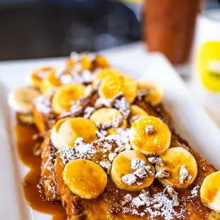 a plate of french toast topped with bananas and powdered sugar