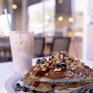 a stack of pancakes with syrup being poured on top