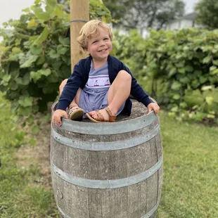 a little boy sitting on a barrel