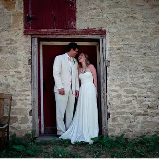 a bride and groom in front of a stone building