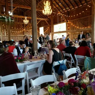 a large group of people sitting at tables in a barn