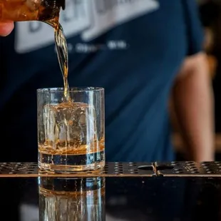 a person pouring a drink into a glass