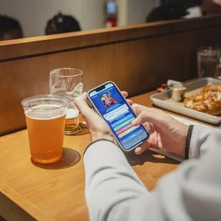 a man sitting at a table with a glass of beer and a cell phone