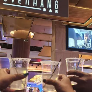 two people holding drinks and a television