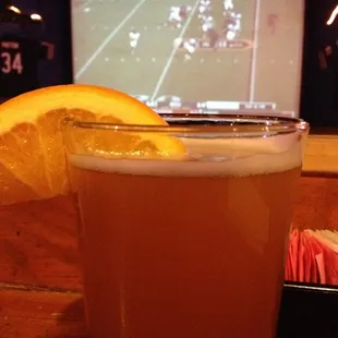 a glass of beer with a slice of orange