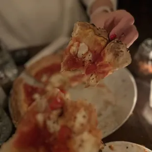 a hand holding a slice of pizza
