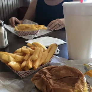 a woman sitting at a table with a hamburger and fries