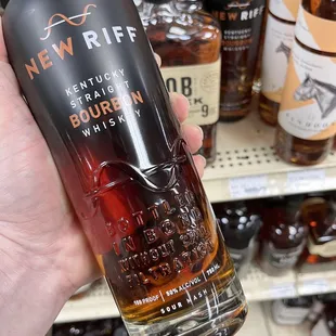 a hand holding a bottle of new riff bourbon