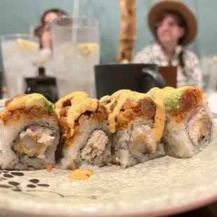 a plate of sushi with a woman in the background