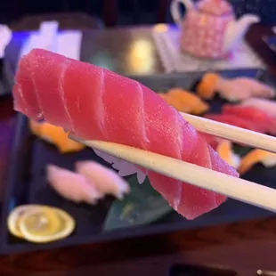 chopsticks holding a piece of sushi