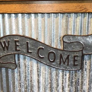 a welcome sign on a corrugated wall