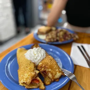 a plate of pancakes with whipped cream and strawberries