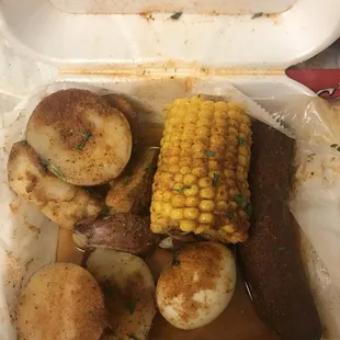 corn, potatoes, and sausage in a styrofoam container