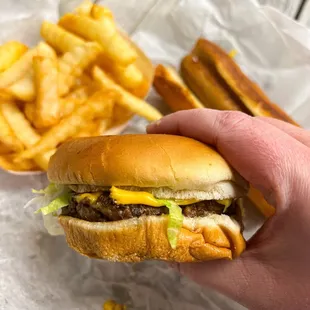  a hand holding a cheeseburger and french fries