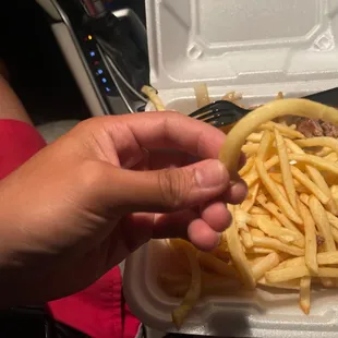 a hand holding a piece of french fries