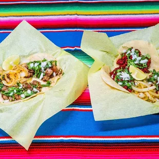 two tacoss on a colorful table cloth