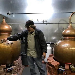 a man standing in front of two copper pots