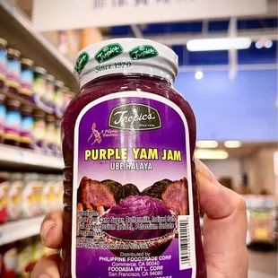 a hand holding a jar of purple yam jam