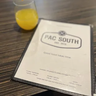 a menu and a glass of orange juice