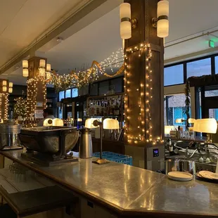 a restaurant with a long bar with lights strung from the ceiling