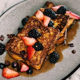 Creme Brulee French Toast Stack with brioche, maple syrup, guanciale crumbles, berries at Pacific Standard Prime steakhouse in Redondo Beach
