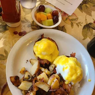 Eggs Benedict with potatoes and fresh fruit