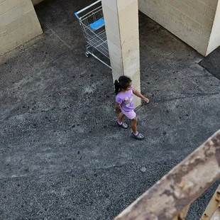 a little girl in a purple dress walking up a ramp