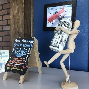 a wooden mannequin holding a can of beer