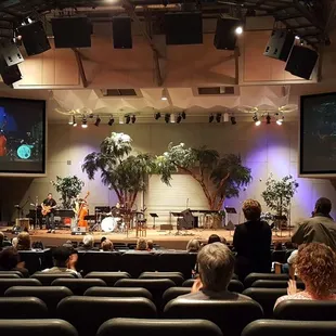 people sitting in chairs in front of a stage