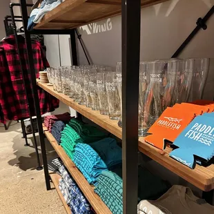 a shelf of beer glasses and t - shirts