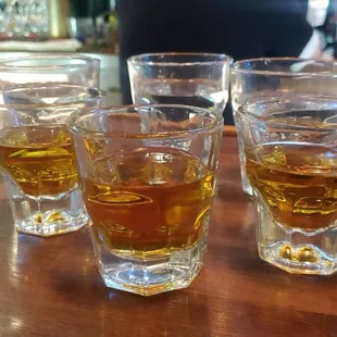 four glasses of whiskey on a bar