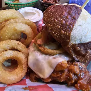 Hog Heaven: barbecue pulled pork, bacon, onion rings, and havarti cheese on a pretzel bun, with a side of onion rings.