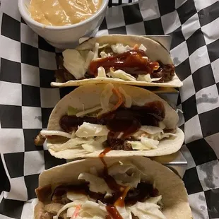 three tacos on a checkered tray