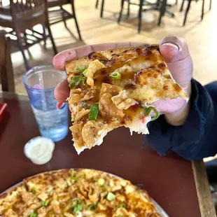 a hand holding a piece of pizza