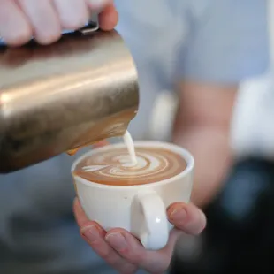 a person pouring milk into a cup