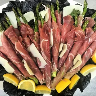 Fresh, grilled asparagus rolled in prosciutto with shaved asiago cheese in light lemon vinaigrette